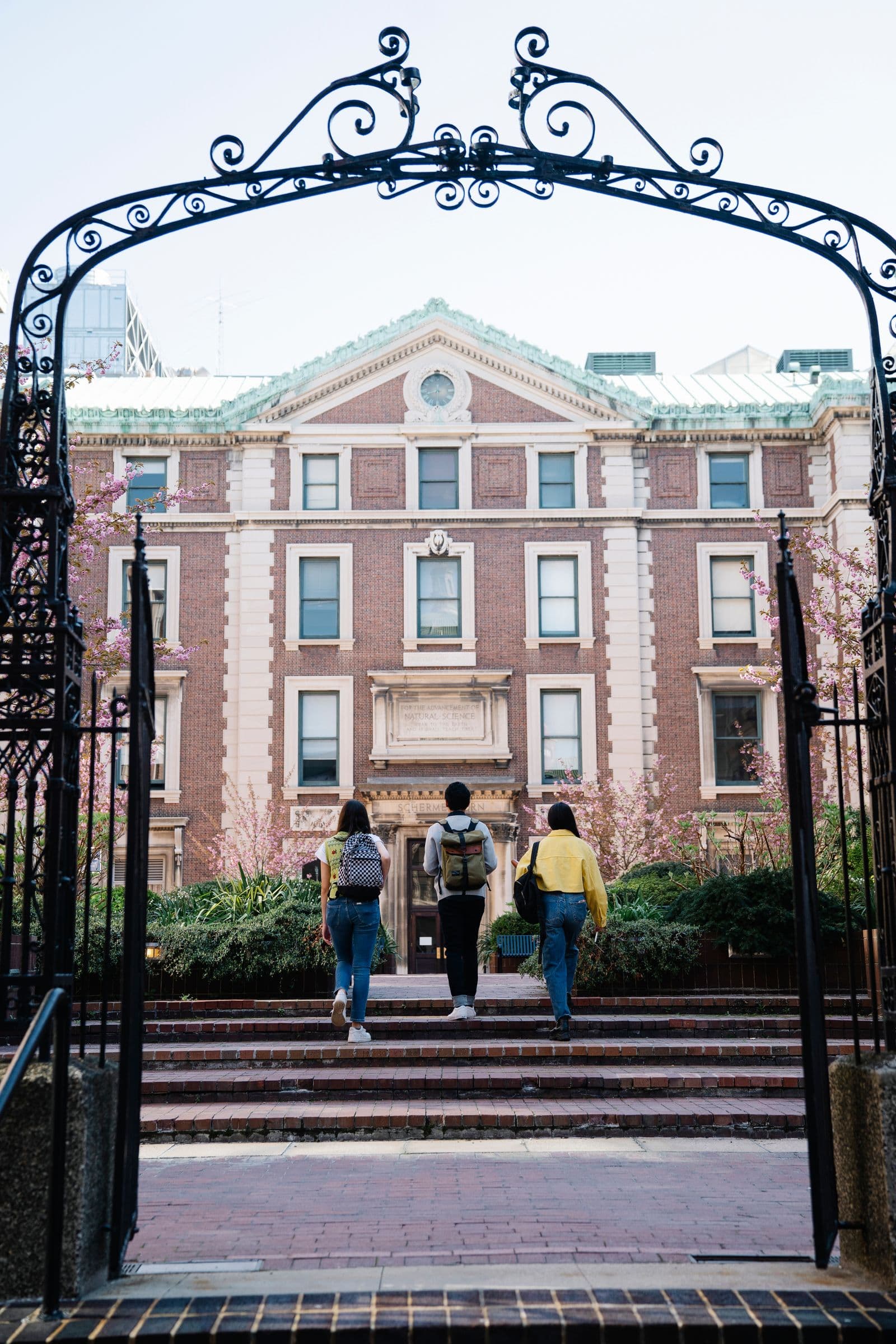Students walking into the campus of a red-brick European university
